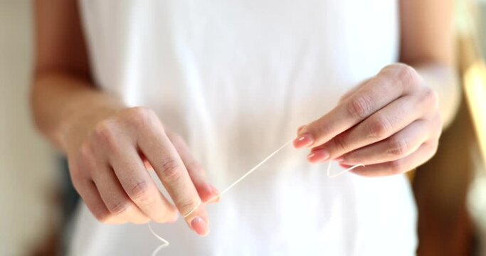 Woman hands uses dental floss for brushing teeth and oral hygiene at home