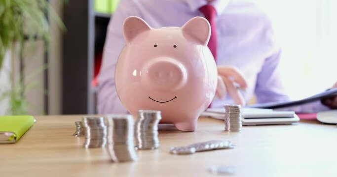 Businessman accounting tax consultant using a calculator and piggy bank considers business budget