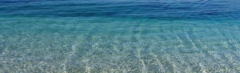 Crystal clear, seawater in various shades of blue with fine gravel as substrate. Beautiful structure and light effects from the sun shining in. Copy space for your design or product. Web banner.