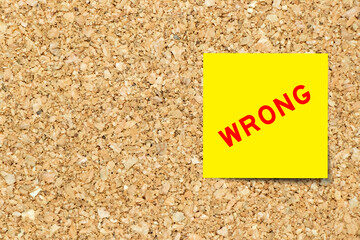 Yellow note paper with word wrong on cork board background with copy space