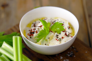Celery sticks with white sauce in a bowl. Healthy food.