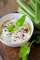 Celery sticks with white sauce in a bowl. Healthy food.