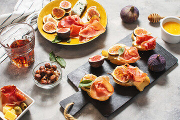 Appetizers board with traditional spanish tapas set. Italian antipasti bruschetta with prosciutto, cream cheese and fig.