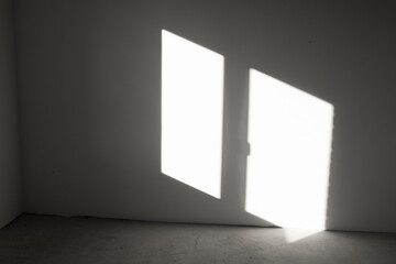 Window-shaped sunlight hitting a dark gray wall inside an empty room. Abstract background with geometric lines.