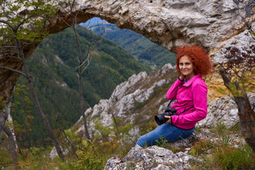 Naklejka na ściany i meble Woman tourist with camera by a natural rock portal