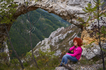 Naklejka na ściany i meble Woman tourist with camera by a natural rock portal