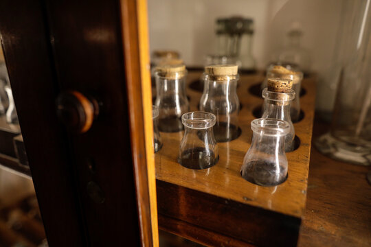 Shallow depth of field (selective focus) details with various glass vials used for old chemical and medical experiments inside a museum.