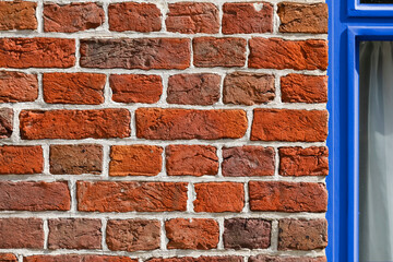 Wall of red brick with a part of blue window frame