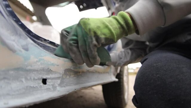 Car preparation for body painting. Polishing and leveling putty with sandpaper.