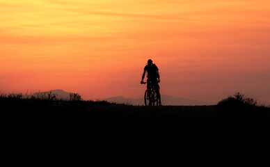 Fototapeta premium Mountain bilker on a trail at sunset