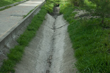 Fototapeta na wymiar concrete gutter next to the path, green grass all around