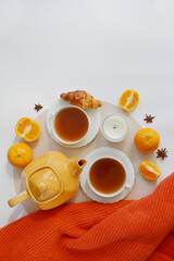 Two cups of tea, teapot, candle, mandarins on the white background.  Home atmosphere. Orange tea flavor. Stay healthy in flu winter autumn days. Autumn fall tea composition. Place fot text.