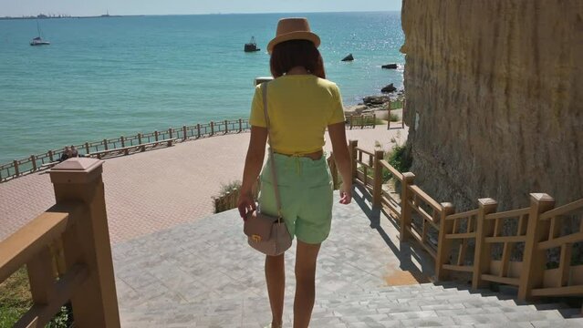 Woman with hat walking down stairs in Aktau Kazakhstan. 4k footage UHD 3840x2160 