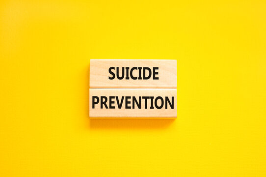 Suicide prevention symbol. Concept words Suicide prevention on wooden blocks. Beautiful yellow table yellow background. Psychological and suicide prevention concept. Copy space.