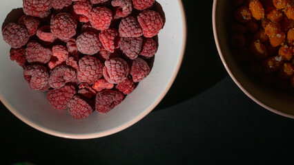 Top view of two glass plates with frozen raspberries inside on the black background. healthcare, healthy food concept, Ripe berries with frosty freshness, agriculture. soft focus, selective focus.