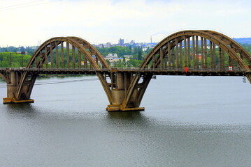 Fototapeta premium Railway arch bridge over Dnipro river, view of Dnepr city, autumn cityscape. Old vintage bridge