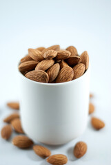 Tasty almond in a white cup isolated on white background, selective focus.