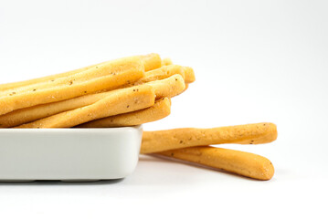Tasty seaweed breadsticks are housed in white ceramic vessels and placed on a white floor selective focus, space for text.