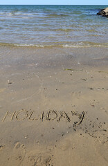 big capital letters text HOLIDAY on the sand of the beach