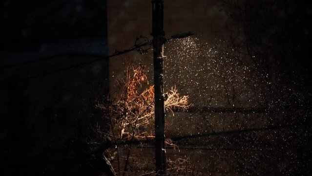 Snow slowly flies in the light of the lantern. Falling snow in the light of a lantern. A blizzard in the city at night. The light of a lantern at night in the city in winter.