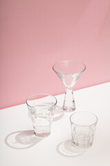 Photo of a modern stylish cocktail, alcohol glasses shot in trendy minimalistic style on a white table with pink background