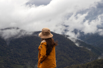 Woman relaxing the view of fog in the forest with green mountains. Life is beautiful.