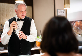 Mature waiter serving cocktails to a couple in a luxury hotel