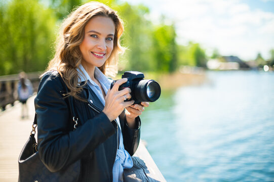 Young smiling woman holding a reflex camera outdoor