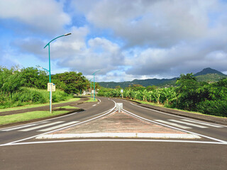 Panoramic of road crossing with pedestrian crossings in Caribbean landscape with tropical vegetation and blue sky of the French Antilles. Roundabout without traffic.