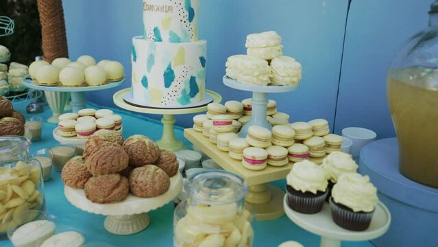 Buffet with sweets on holiday. Tender airy marshmallows, macaroons, freshly baked cupcakes, crispy cookies, shu cake with custard, mousse desserts and juice in jar on festive table. Delicious banquet