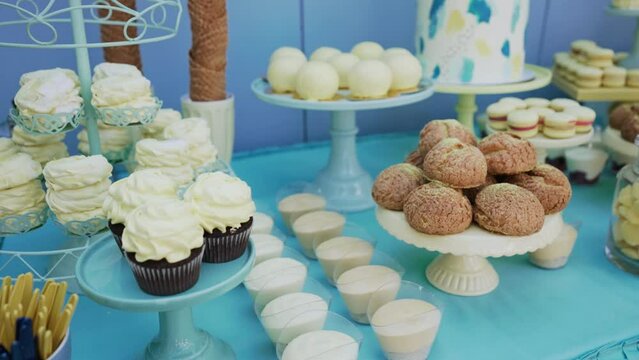 Buffet with sweets on holiday. Tender airy marshmallows, macaroons, freshly baked cupcakes, crispy cookies, shu cake with custard, mousse desserts and juice in jar on festive table. Delicious banquet