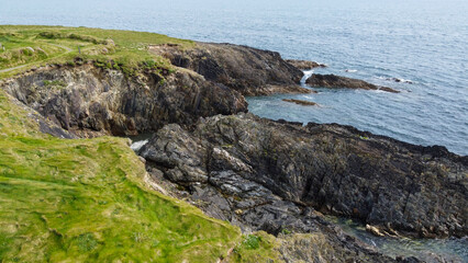Fototapeta na wymiar Drone point of view. Beautiful Irish coast of the Atlantic Ocean, top view. Nature of Northern Europe. Coastal rocks covered with green grass. Aerial photo.