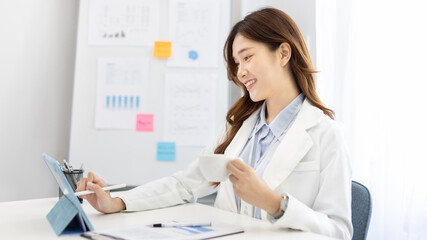 Businesswoman using laptop to work, Asian woman working in the office, Financial clerk or accountant with documents and equipment working on the desk, Using tablet for financial transactions.