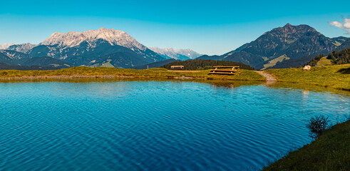 Beautiful alpine summer view with the famous Leoganger Steinberge mountains in the background and reflections in a lake at Fieberbrunn, Tyrol, Austria