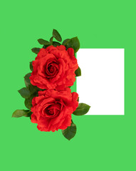 Red roses on green background next to blank paper, space for text