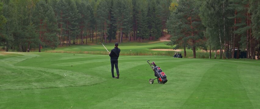 Caucasian man playing golf, striking a ball during the course