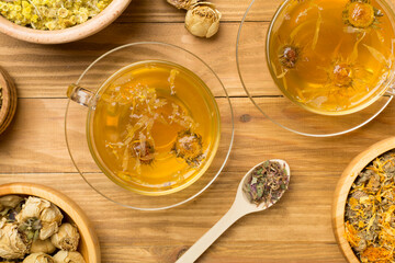 Herbal tea with ingredients on wooden background, top view