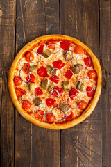 Pizza with tomato, red pepper and eggplant. On a wooden table.