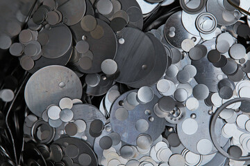 Shiny metallic background.Metal scraps of a flat round shape. Production of bearings in production. Perforation of metal tape.
