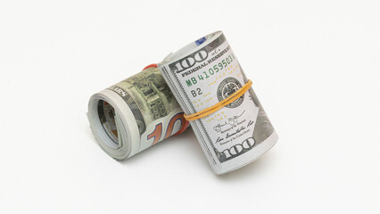Fototapeta premium Hundred dollar bills rolled up with rubber band on isolated white background