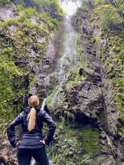 Blond woman standing in front of waterfall in rainy black forest, Germany