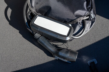 Portable in-cable charging box for electric car charging lying in a car trunk.