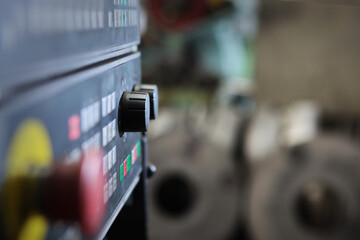 Control panel with red button on the production of bearings.Concept of the industrial industry.Blanks for large diameter bearings are out of focus in background.Selective focus.