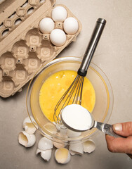 whisking eggs in glass mixing bowl