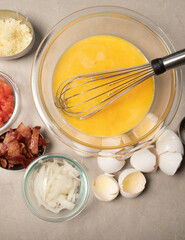 Preparing egg bites with bacon tomatoes onions and cheese
