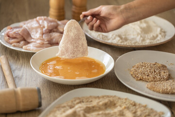 Breading of chicken breasts while putting them to flour and eggs during schnitzels making