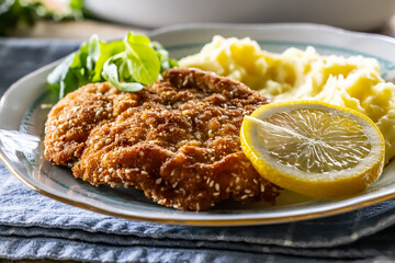 Tasty fried schnitzel served with mashed potatoes and greens with a slice of lemon