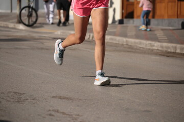 Fototapeta na wymiar runner feet on the asphalt in a city race shoes mussles legs soprts
