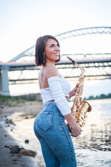 Woman playing the saxophone at sunset.
