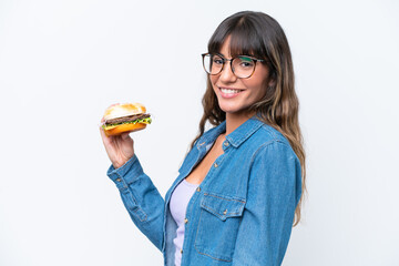 Young caucasian woman holding a burger isolated on white background smiling a lot